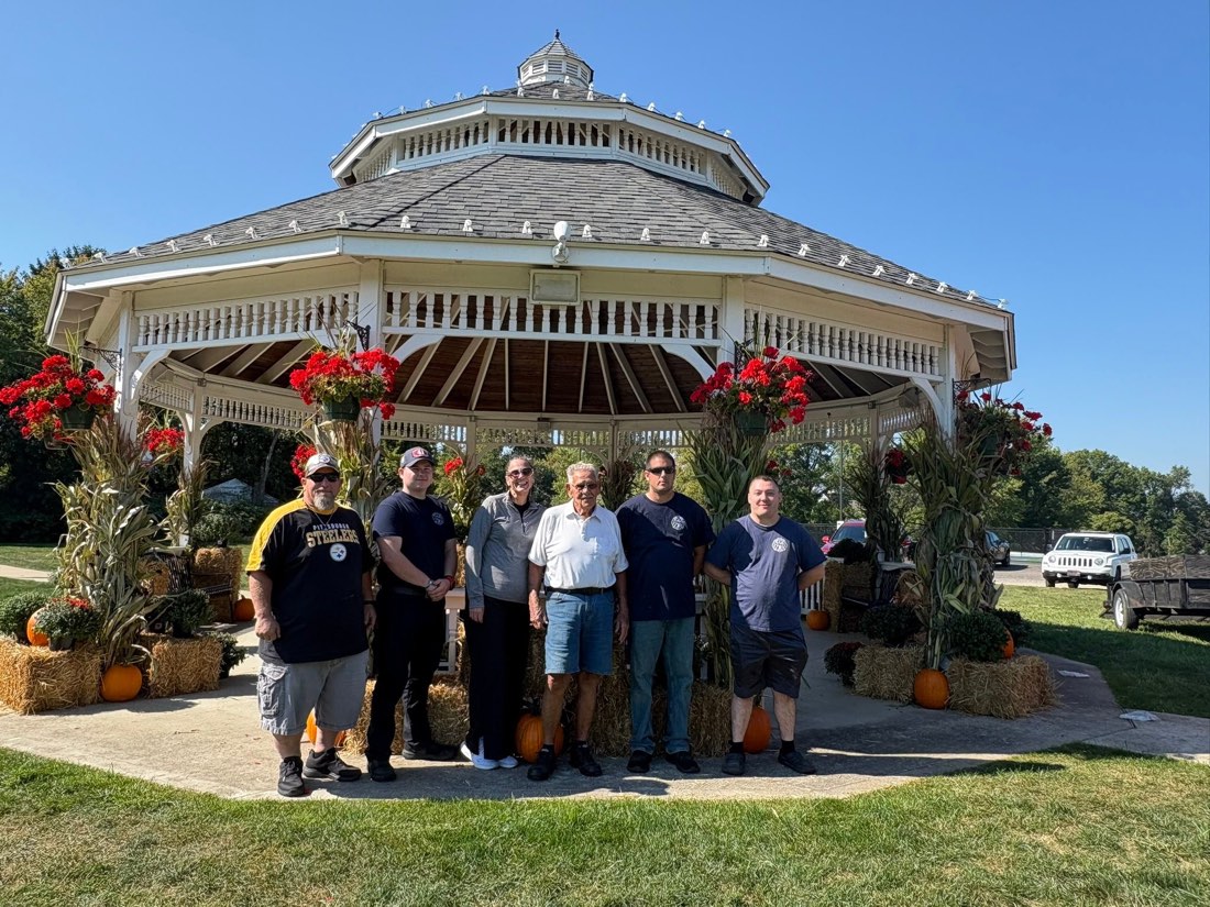 Community members standing together in front of the gazebo decorated for fall